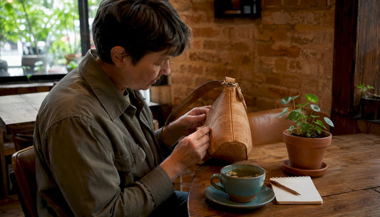 Person inspecting cork handbag at workspace