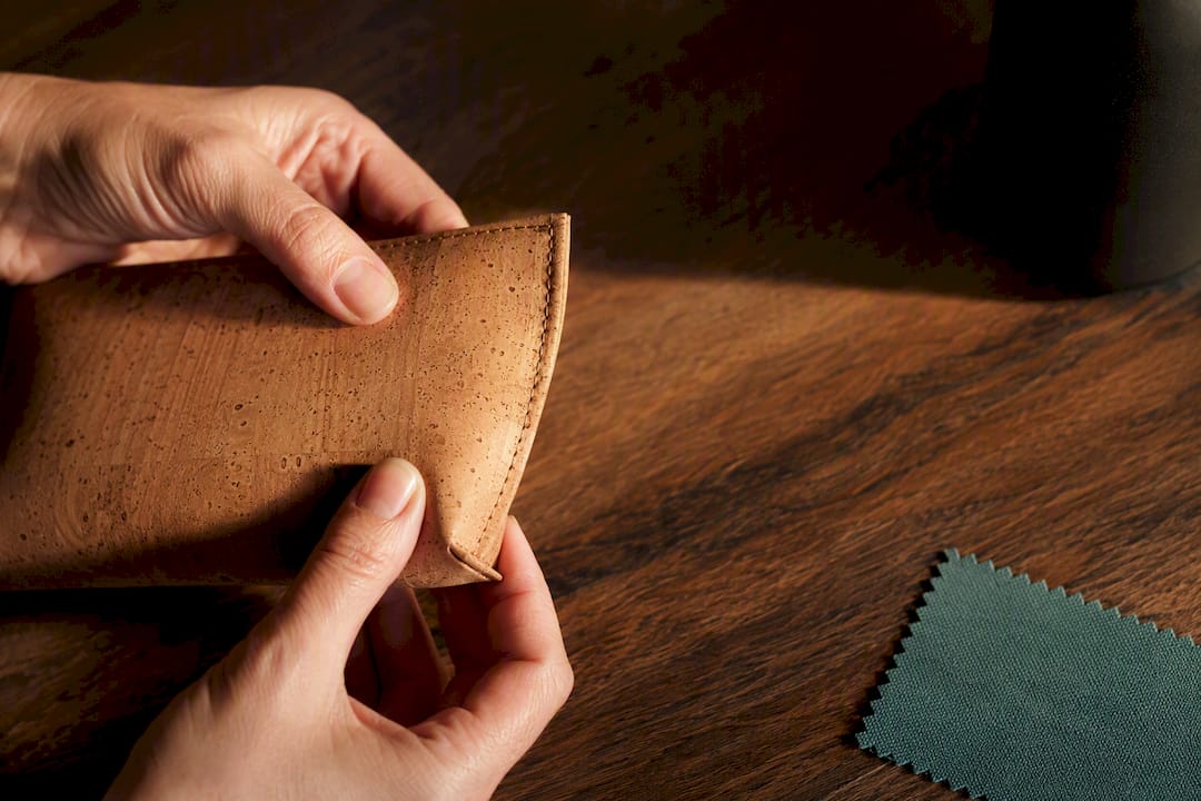 Hands examining a stitched cork purse edge